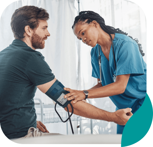 A nurse in blue scrubs checks a seated man's blood pressure with a cuff as they discuss options for depression therapy in Nashville TN, all within a bright medical setting.