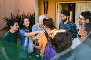 A group of people gather outside a house, smiling and greeting each other warmly—some hugging, others chatting nearby—enjoying the moment together and supporting each other's journey with behavioral health in Nashville TN.