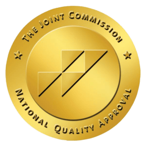 A gold circular seal with "The Joint Commission National Quality Approval" around the edge and a geometric logo in the center, representing high standards for behavioral health in Nashville TN.